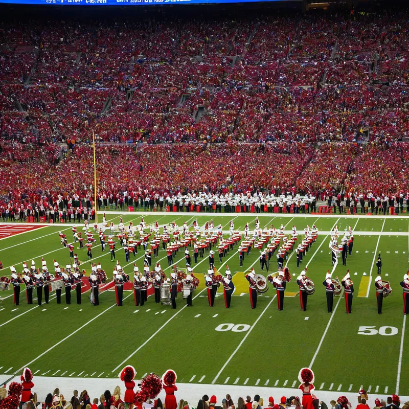 Halftime Show - A high-energy, colorful image of a marching band and cheerleaders performing during the halftime show of a football game, with the stadium crowd in the background. - AI image generated with Photorealistic - over-the-shoulder