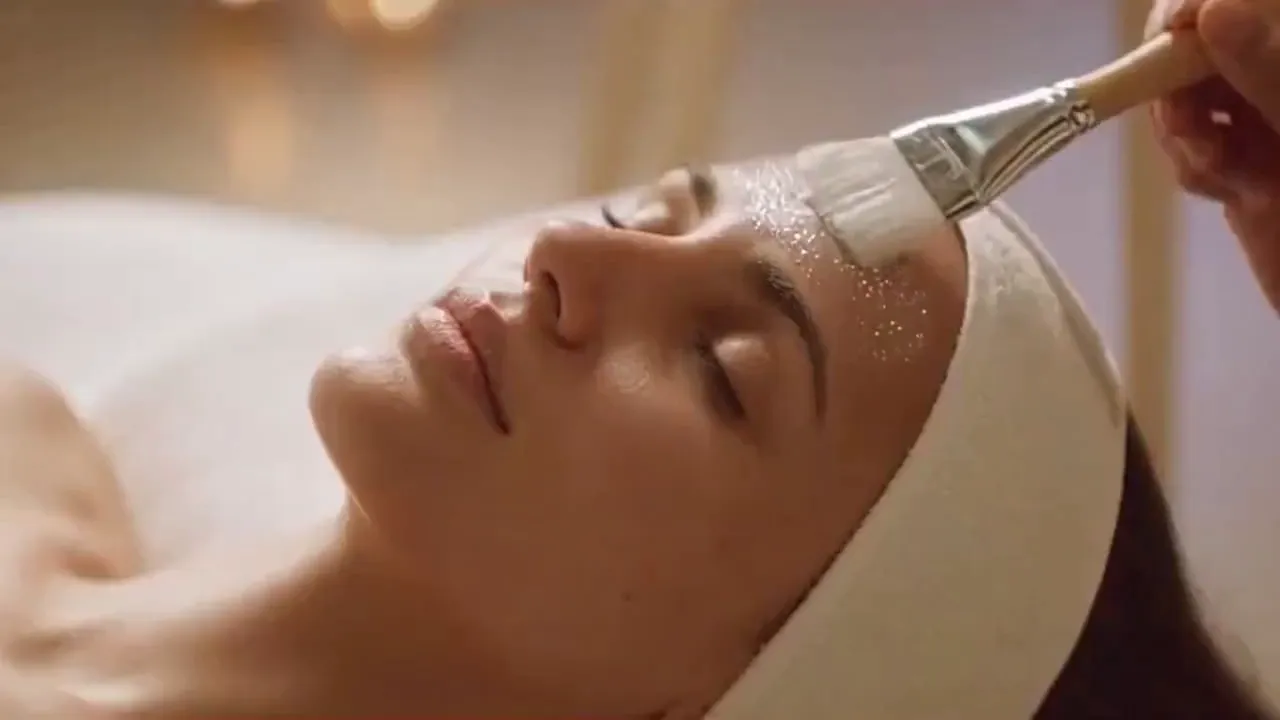 Luxurious Diamond-Infused Spa Facial - A hyper-realistic, cinematic spa facial scene. A serene woman lies on a plush treatment bed in a softly lit luxury spa. A professional esthetician gently applies a translucent facial mask infused with tiny, super-sparkly diamond particles that catch the light and shimmer subtly. The diamonds appear microscopic and elegant, embedded in the skincare formula — never chunky or costume-like.

The camera moves slowly in smooth, calming motions: close-ups of glowing skin, soft brush strokes across the face, diamond particles reflecting light like fine stardust. Skin texture looks natural and hydrated with a dewy glow. The overall mood is peaceful, elevated, and indulgent.

Lighting is warm and diffused with soft highlights, neutral spa tones (ivory, champagne, lavender accents). The woman looks relaxed, eyes closed, breathing calmly. Ultra-realistic skin details, shallow depth of field, cinematic bokeh, 4K quality, slow motion moments, luxury skincare commercial aesthetic. - AI video generated with Sora 2